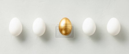 Foto de White chicken eggs with one golden egg flat lay top view banner. standing out from the crowd - Imagen libre de derechos