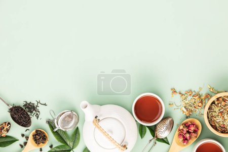 Una puesta plana bien organizada con una variedad de tés de hoja suelta, una tetera blanca y accesorios de té sobre un fondo verde pastel suave, que representa una escena serena de preparación de té.