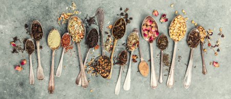 Foto de Una variedad de cucharas vintage, cada una llena de diferentes tipos de tés y hierbas, dispuestos en una superficie gris rústica, que muestra la diversidad de sabores y fragancias. Banner - Imagen libre de derechos