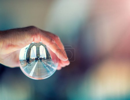 Téléchargez les photos : Main masculine tenant une balle transparente avec des reflets Brooklyn Bridge, New York - en image libre de droit