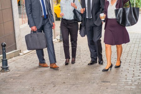 Photo for Business meeting outdoor, four people walking along city streets. Detail on the legs. - Royalty Free Image