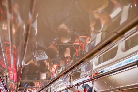 Téléchargez les photos : Réflexions de personnes sur le plafond d'un train dans un métro bondé. Tourisme et concept d'entreprise. - en image libre de droit
