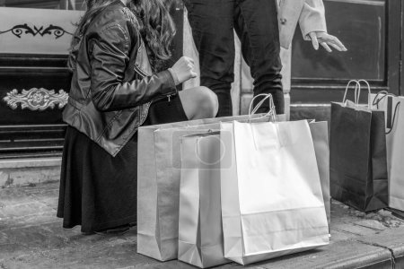 Téléchargez les photos : Deux belles filles faisant du shopping dans les rues de la ville, détail sur les jambes et sacs à provisions. - en image libre de droit