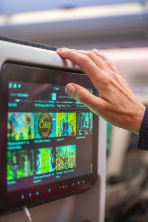 Foto de Mano de mujer interactuando con un moderno sistema de entretenimiento durante un vuelo. - Imagen libre de derechos