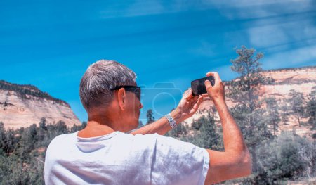 Photo for Back view of male tourist in t-shirt taking pictures of national park. Tourism concept. - Royalty Free Image