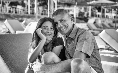 Foto de Happy family resting at beach in summer. Father and daughter together on the beach chair smiling. - Imagen libre de derechos