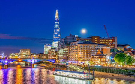 Foto de LONDRES, Reino Unido - 2º JULIO 2015: Ciudad moderna con reflejos del río Támesis por la noche - Imagen libre de derechos