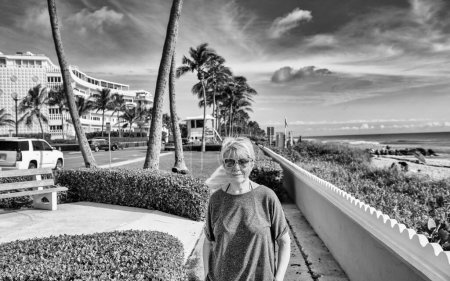 Foto de Elderly woman standing happy along Palm Beach promenade - Imagen libre de derechos