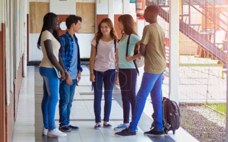 Téléchargez les photos : Des camarades de classe multiethniques parlent dans le couloir de l'école. - en image libre de droit