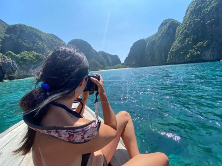 Photo for Woman on a long tail boat taking pictures of Maya Beach, Phi Phi Leh Island, Thailand. - Royalty Free Image