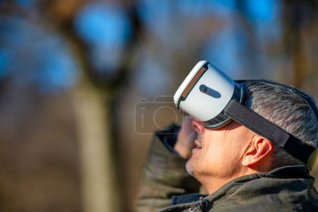Foto de Hombre feliz usando un visor de realidad virtual explorando el parque de la ciudad. - Imagen libre de derechos