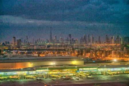 Foto de Aeropuerto de Dubái por la noche con horizonte de la ciudad en el fondo. - Imagen libre de derechos