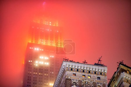 Foto de Ciudad de Nueva York, NY - 2 de diciembre de 2018: El Empire State Building con la parte superior en rojo envuelta por la niebla. - Imagen libre de derechos