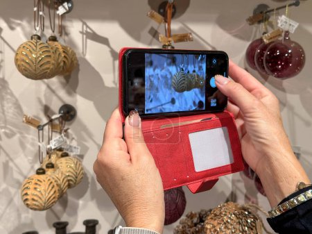 Téléchargez les photos : Femme prenant des photos de belles décorations de Noël avec son smartphone. - en image libre de droit