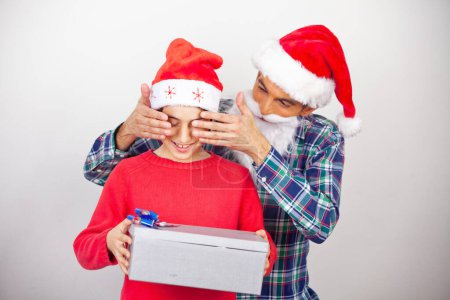 Téléchargez les photos : Homme heureux couvrant les yeux de son fils donnant un cadeau pour Noël. - en image libre de droit