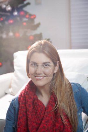 Téléchargez les photos : Femme heureuse à la maison pour la saison des fêtes avec arbre de Noël sur le fond. - en image libre de droit