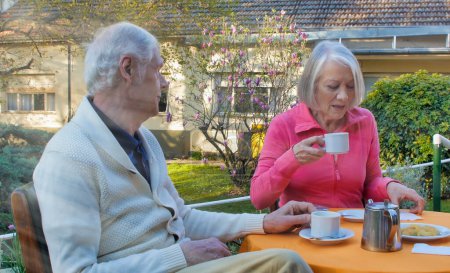 Téléchargez les photos : Couple retraité caucasien prenant le petit déjeuner dans le jardin. Concept de retraite et de détente. - en image libre de droit