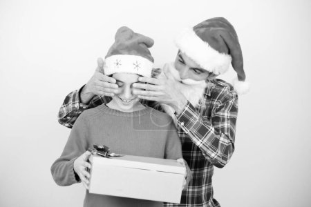 Photo for Happy man covering his son's eyes giving a gift for Christmas. - Royalty Free Image