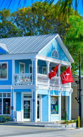 Photo for Key West, Florida - February 20, 2016: Colorful home under a blue sky with red flags from the terraces - Royalty Free Image