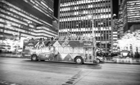 Foto de MANHATTAN, NY - 7 DE DICIEMBRE DE 2018: Tráfico urbano con autobuses turísticos y edificios modernos por la noche - Imagen libre de derechos