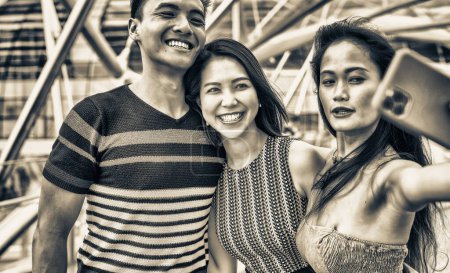 Téléchargez les photos : Trois asiatiques jeunes amis en plein air prendre selfies. Ville vie de deux filles et un garçon. - en image libre de droit