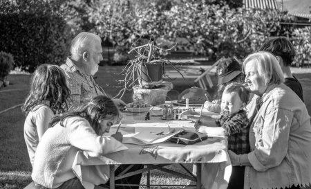 Téléchargez les photos : Grands-parents et petits-enfants jouant ensemble en plein air par un après-midi ensoleillé aux jeux de table - en image libre de droit