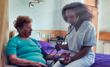 Foto de Médico africano visitando a paciente anciana en cama de hospital. Concepto de rehabilitación y jubilación. - Imagen libre de derechos