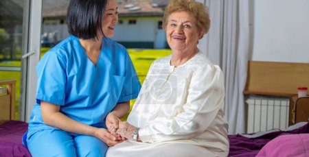 Téléchargez les photos : Femme caucasienne souriant avec infirmière à la clinique de désintox. Les personnes âgées retraitées vivent leur vie à son meilleur - en image libre de droit