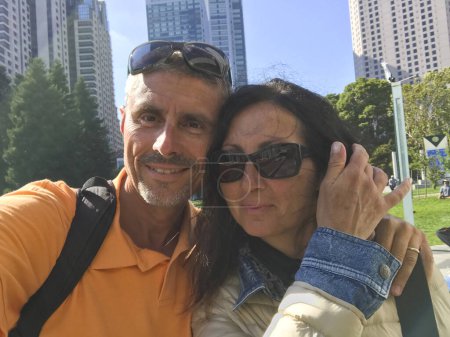 Foto de Happy couple in the forties taking selfies in a square of San Francisco. - Imagen libre de derechos