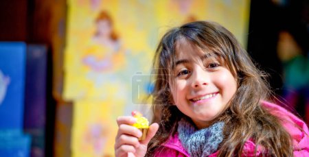 Photo for Happy young girl holding a colorful cake at night in a city street. - Royalty Free Image