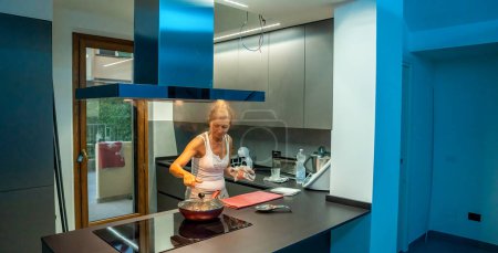 Téléchargez les photos : Moving to a new house. Modern kitchen with a woman cooking meal. - en image libre de droit
