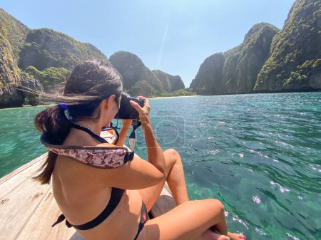 Téléchargez les photos : Femme sur un bateau à longue queue prenant des photos de Maya Beach, Phi Phi Leh Island, Thaïlande. - en image libre de droit