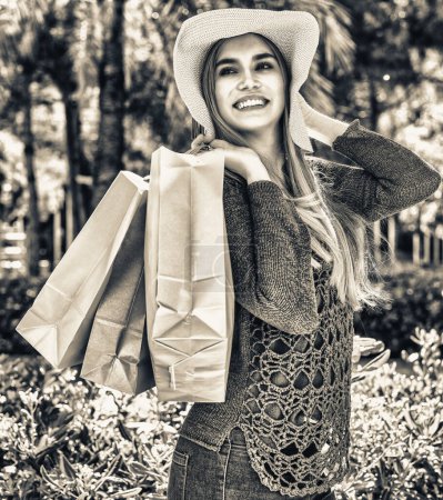 Foto de Hermosa mujer rubia feliz caminando en el parque con coloridas bolsas de regalo
. - Imagen libre de derechos
