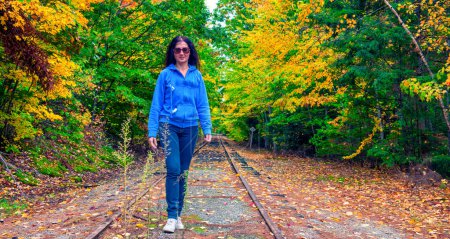 Photo for Woman walking along a trail in fall season. - Royalty Free Image