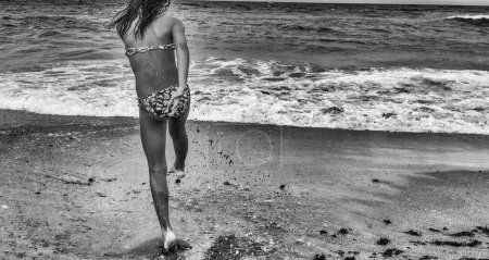 Foto de Young girl on the beach splashing seawater with her feet - Imagen libre de derechos