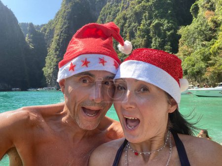 Téléchargez les photos : Noël tropical familial. Couple caucasien portant chapeaux de Noël sur une belle plage. - en image libre de droit