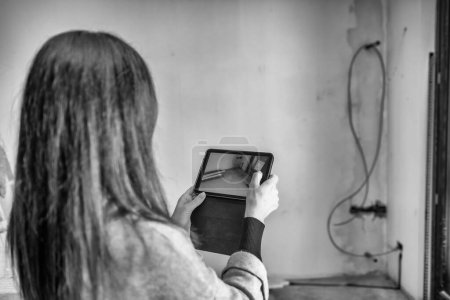 Foto de Mujer colocando objeto en realidad aumentada con una tableta. Mudarse a un nuevo hogar - Imagen libre de derechos