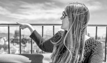 Photo for Happy young woman enjoying city view from rooftop on a sunny day. - Royalty Free Image