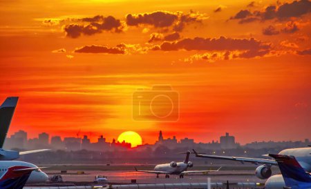 Téléchargez les photos : Backlit view of airplanes on the airport runway at sunset. Travel around the world concept. - en image libre de droit