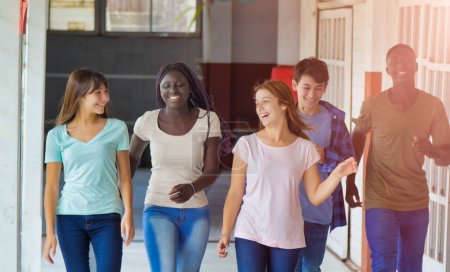 Foto de Feliz grupo multiétnico de adolescentes en la escuela caminando por el pasillo. Concepto de felicidad y ligereza. - Imagen libre de derechos