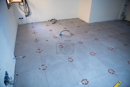 Foto de Colocando las baldosas en el piso de la sala del sótano. Mudarse a un nuevo concepto de casa. - Imagen libre de derechos
