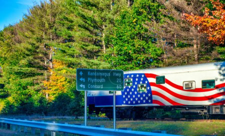 Téléchargez les photos : Grand camion avec drapeau américain le long d'une route en saison des feuillages. - en image libre de droit