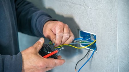 Foto de Electricista monta un enchufe eléctrico a la pared, cables de conexión. - Imagen libre de derechos
