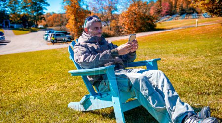 Téléchargez les photos : Homme relaxant sur une grande chaise dans un parc, saison d'automne, - en image libre de droit