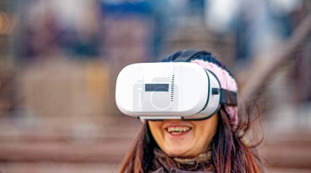 Téléchargez les photos : Femme heureuse portant une visière de réalité virtuelle explorant la ville. - en image libre de droit