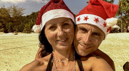 Photo for Family Tropical Christmas. Caucasian couple wearing Christmas Hats on a beautiful beach. - Royalty Free Image