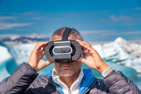 Photo for A man with a virtual reality visor explores the beautiful Jokulsarlon Beach full of icebergs. - Royalty Free Image