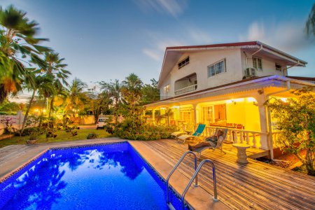 Téléchargez les photos : Night view of a tropical house with pool and palms. - en image libre de droit