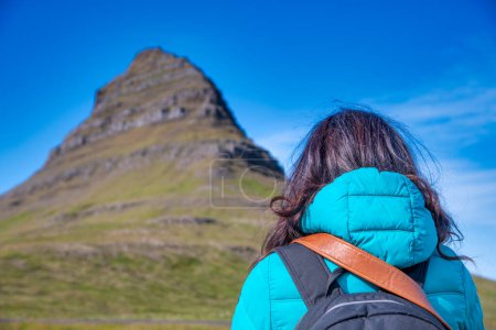 Téléchargez les photos : Une femme regarde la montagne Kirkjufell par une journée ensoleillée, Islande. - en image libre de droit