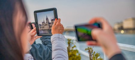 Photo for Tourists taking pictures of Budapest Parliament at sunset - Royalty Free Image